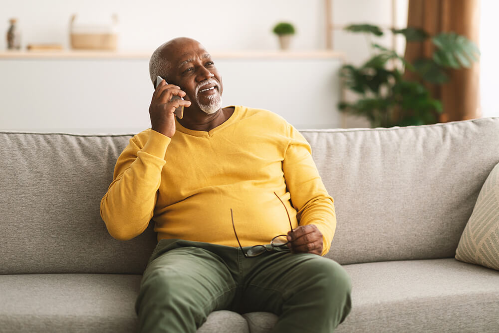 Holding his glasses in his lap, a man sits on a couch, talks on the phone and smiles. The Clarkson Firm Birmingham disability law provides the personal care and attention you deserve.