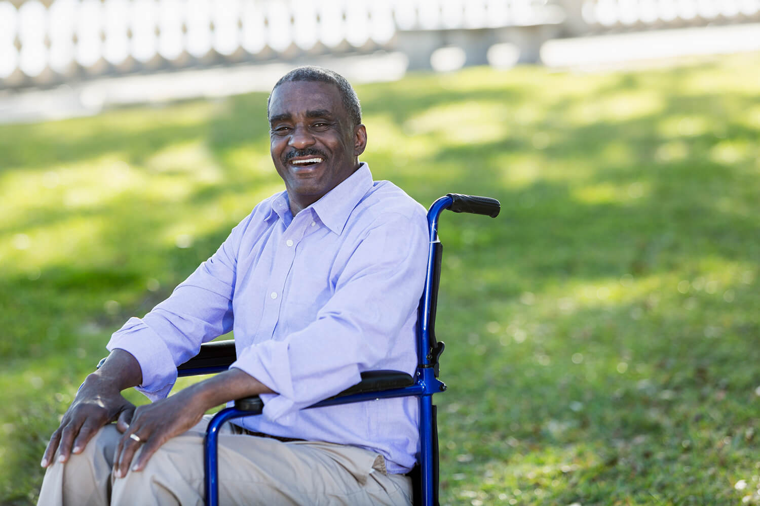 Sitting in a wheelchair in a park, a man smiles for the camera. The Alabama disability lawyers at The Clarkson Firm can help you get SSI benefits.