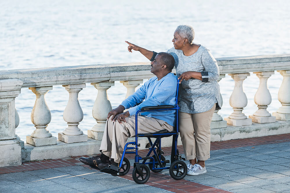 While a man looks over a body of water from his wheelchair, a woman he's with points at something in the distance. The Clarkson Firm disability attorneys can answer questions about getting Social Security Disability benefits.