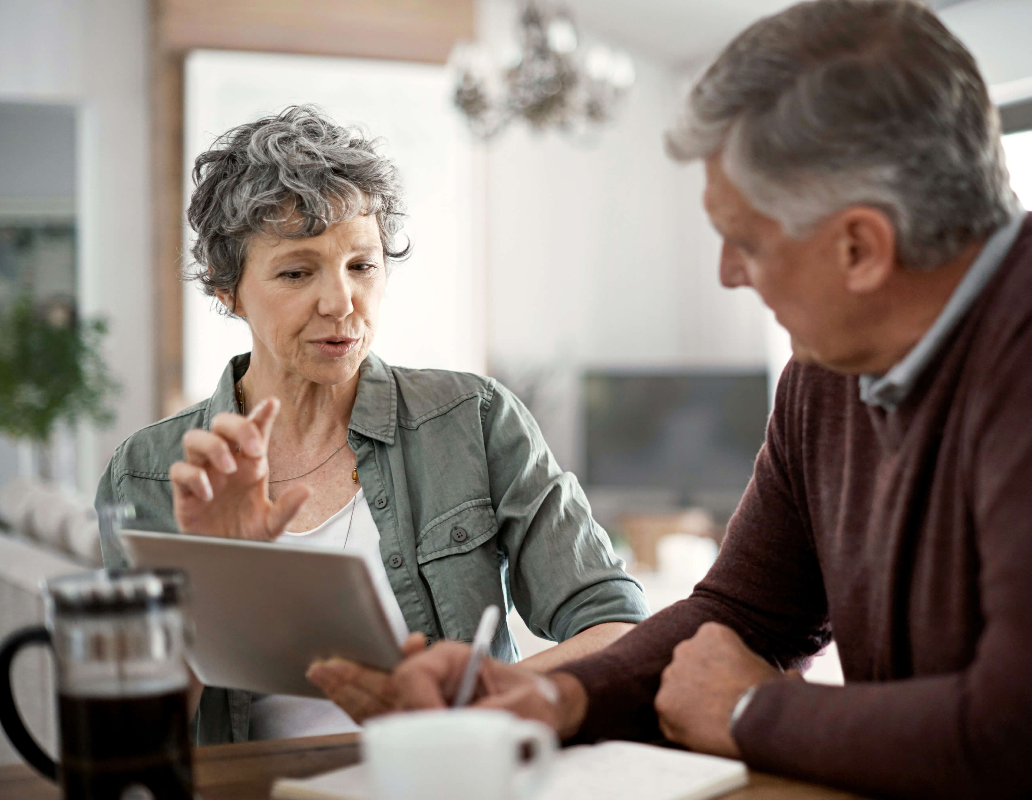 Seated at a dining room table, a woman and man go over paperwork. Social Security Disability lawyers help with the legwork of applying for disability benefits.