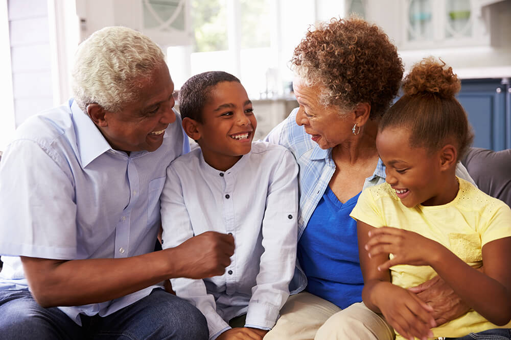 A senior man and woman smiling with a young girl and boy. Social Security Disability survivor benefits are available for family members of benefits recipients who died.