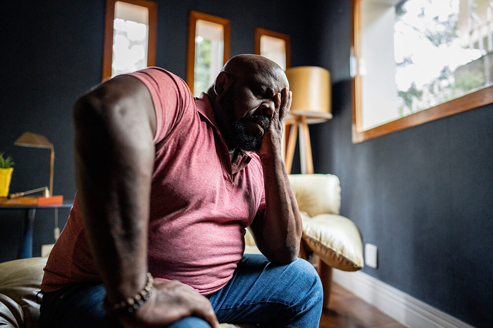 A man rubs his face as he sits in his living room. If you worked and paid into the system enough, you may qualify for Social Security Disability Insurance (SSDI).