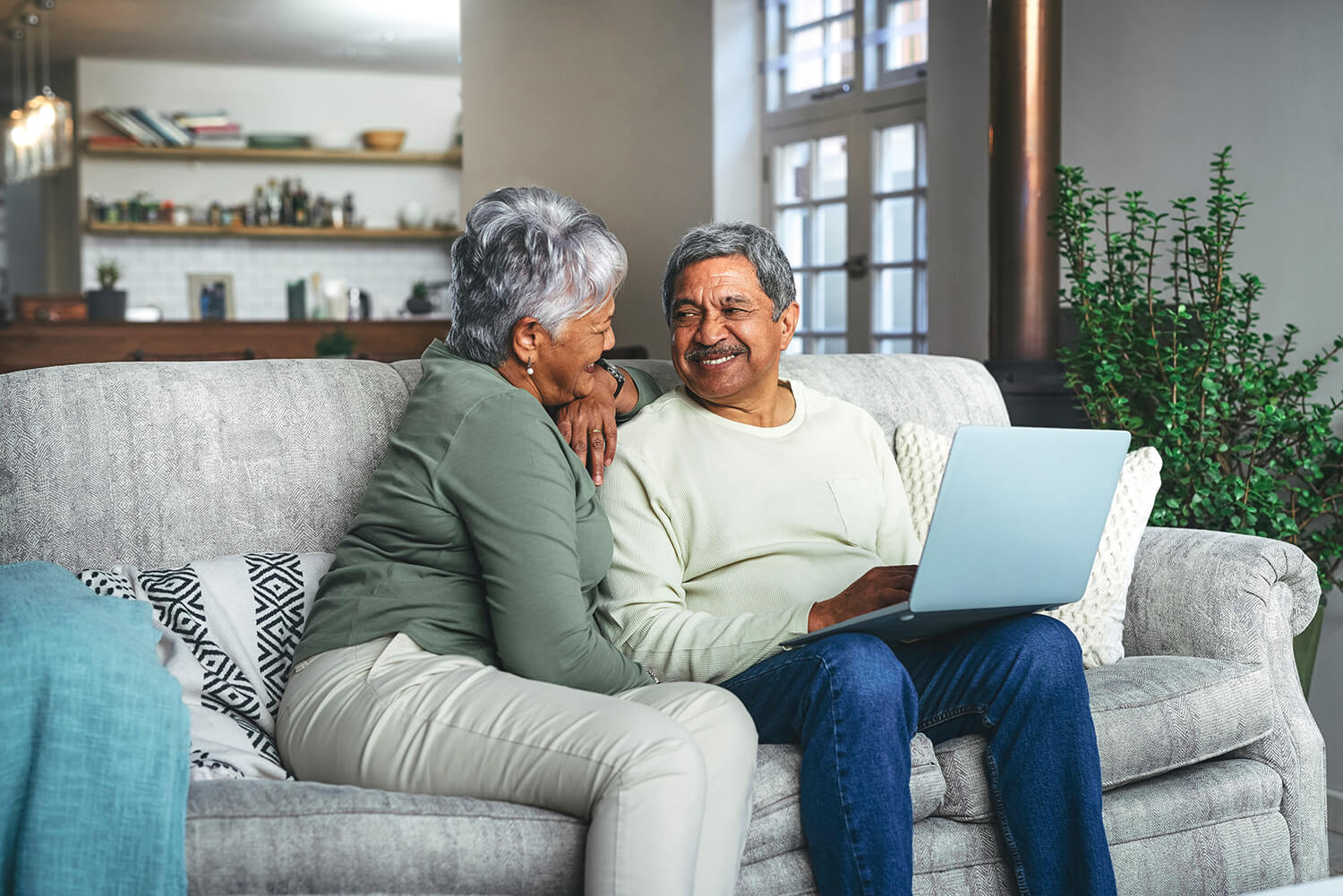 A man with a laptop on his knees smiles at a woman as they sit on a couch. The Clarkson Firm disability attorneys can answer questions about getting Social Security Disability benefits.