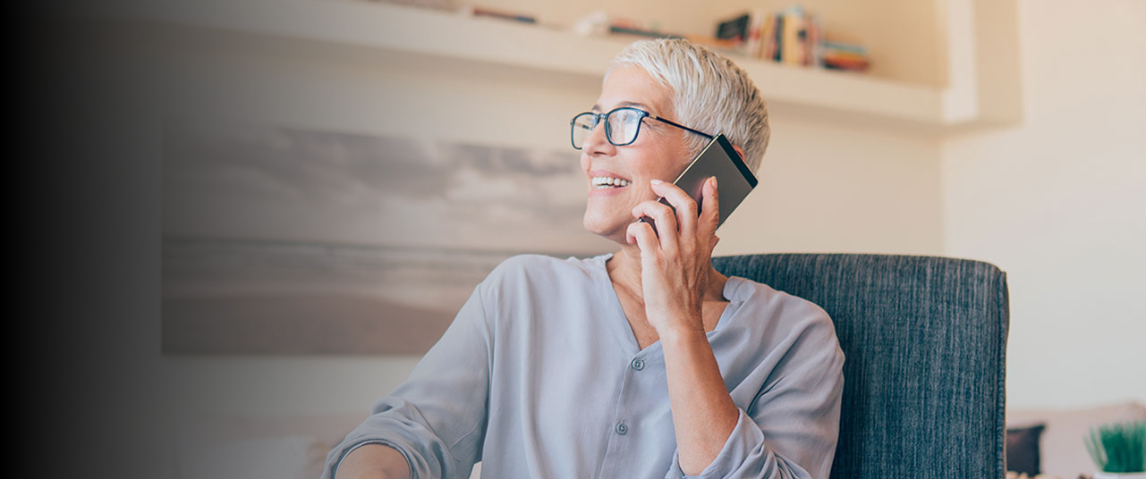 A woman looks to the side and smiles while talking on her phone. You can contact our Alabama disability law firm, The Clarkson Firm, by phone or online.