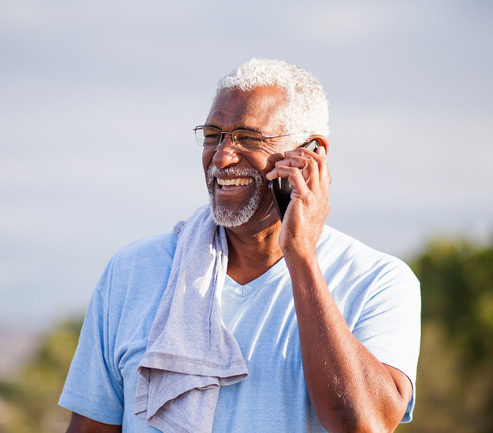 Outdoors on a sunny day, a map holds his phone to his ear and smiles. The Clarkson Firm disability attorneys can answer questions about getting Social Security Disability benefits.