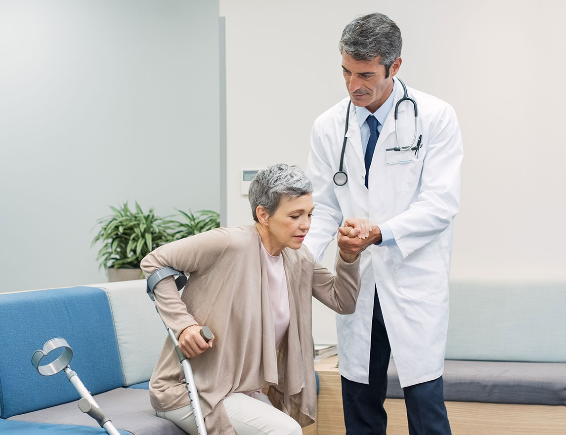 A doctor helps a woman with crutches get up from a waiting room seat. The Clarkson Firm disability attorneys help you prepare for the Social Security Disability application process.